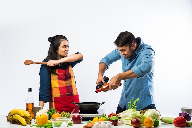 Indisches Paar in der Küche - Junge schöne asiatische Frau, die das Kochen mit Ehemann mit viel frischem Gemüse und Obst genießt