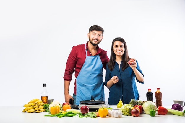 Indisches Paar in der Küche - Junge schöne asiatische Frau, die das Kochen mit Ehemann mit viel frischem Gemüse und Obst genießt