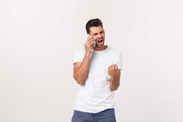 Foto individuo sonriente que habla en un teléfono móvil aislado en la pared blanca.