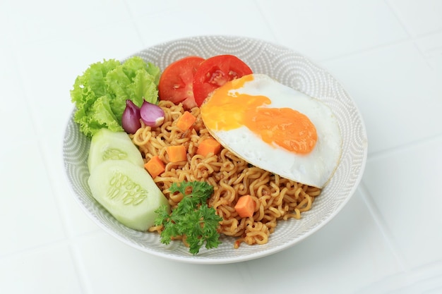 Indomie Goreng Instant Fried Noodle Beliebt aus Indonesien, serviert mit Karotten-Gurken-Tomaten-Schalotten-Salat und Spiegelei