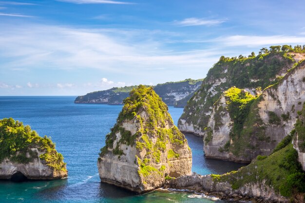 Indonesia. La orilla del océano de una isla rocosa. Algunas cabañas en lo alto de un acantilado entre la selva tropical.