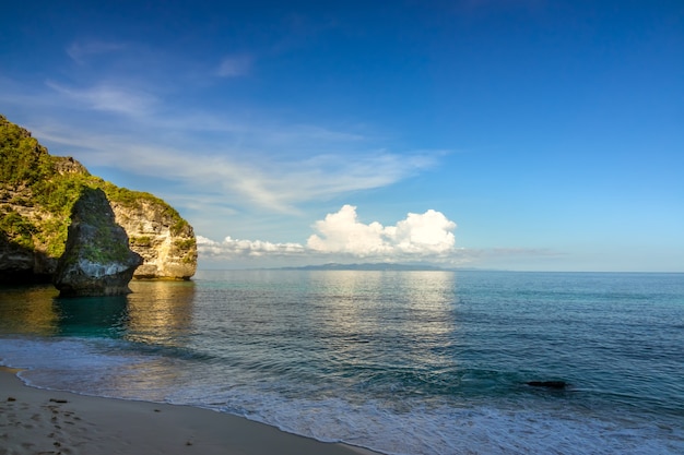 Indonesia. Tarde en una playa sombría vacía en una isla tropical. El cielo azul y las nubes brillantes iluminadas por el sol sobre una isla distante en el océano