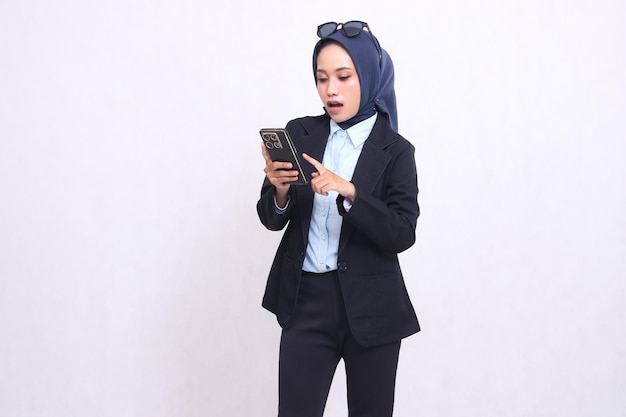 Indonesien reife Bürofrau im Hijab steht überrascht und trägt und drückt Smartphone-Gadget sc