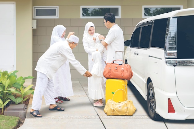 Indonesische muslimische Familie mit Reisetaschen und einem Koffer, der sich von den Eltern verabschiedet