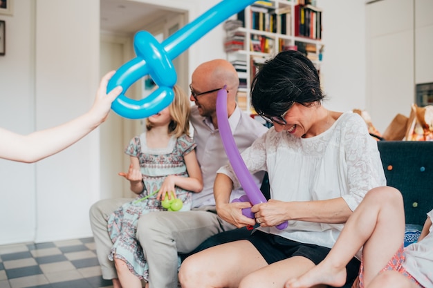 Indoor-Sitzcouch der Familie, die mit Ballonspielzeug spielt