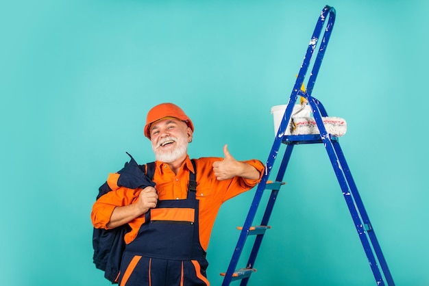 Industria. Haciendo herramienta de reparación. Pintor que trabaja en el sitio de construcción. hombre mayor usa el rodillo en la escalera. trabajo en departamento. Artesano con rodillo de pintura. Negocio de Pintura y Renovación de Viviendas.