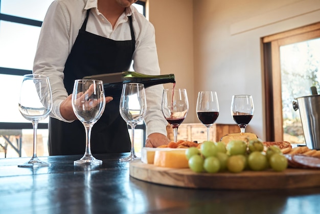 La industria de la hospitalidad y el servicio de vinos de lujo con camarero sirviendo copas se preparan para la degustación de vinos en el restaurante Sumiller profesional que se prepara para una excelente experiencia gastronómica con alcohol