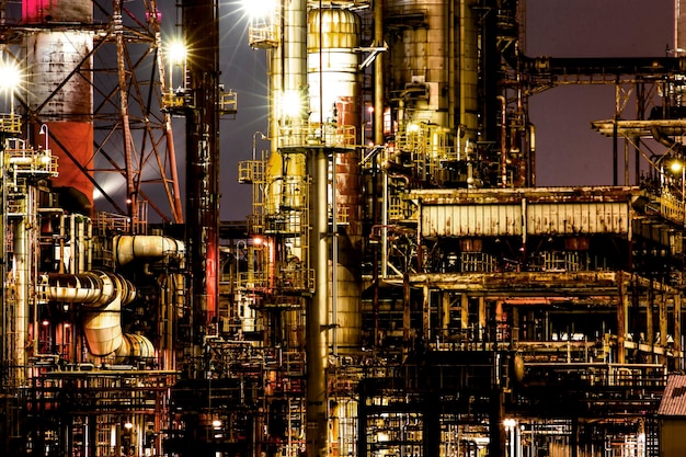 La industria petrolera iluminada contra el cielo por la noche.