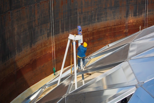 La industria química del trabajador masculino del petróleo y del gas con la cúpula del tanque de almacenamiento del techo superior del combustible de aluminio.