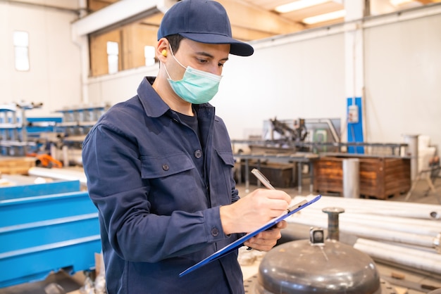 Industriearbeiter, der auf ein Dokument in einer Fabrik schreibt