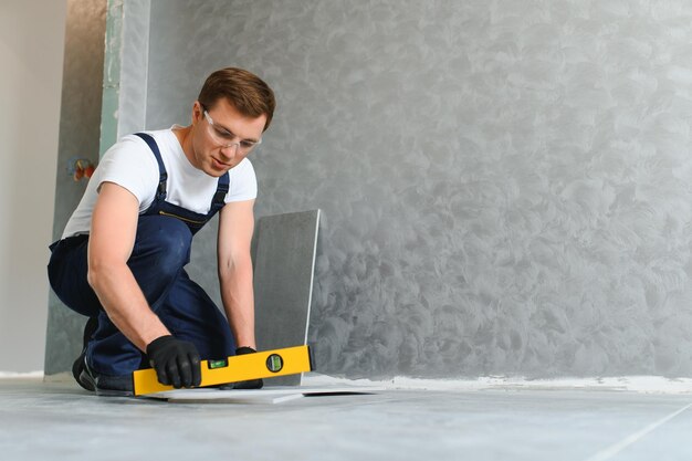 Foto industriearbeiter, handwerker, der keramikfliesen verlegt