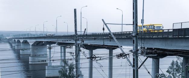 Industrielandschaft - Straßenbrücke über einen breiten Fluss und Eisenbahndrähte im Vordergrund