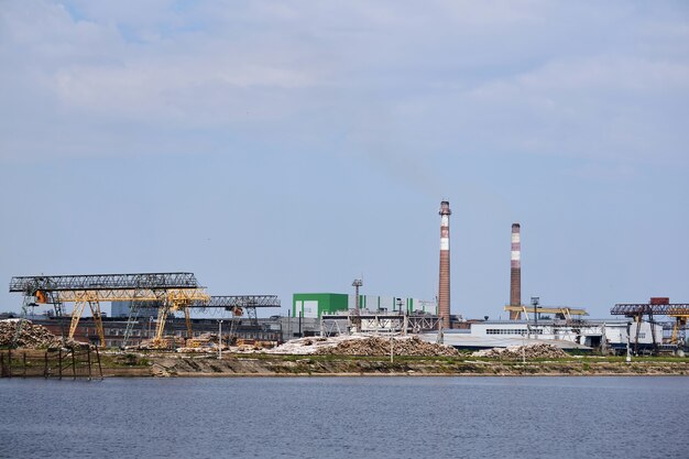 Industrielandschaft, Zellstoff- und Papierfabrik mit Holzstapeln und Schornsteinen am Fluss