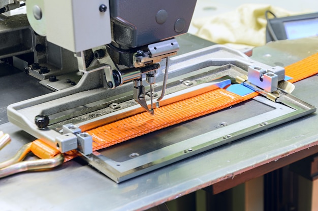 Industrienähmaschine näht einen Ratschengurt. Herstellung von textilen Hebegurten und Bindebändern.
