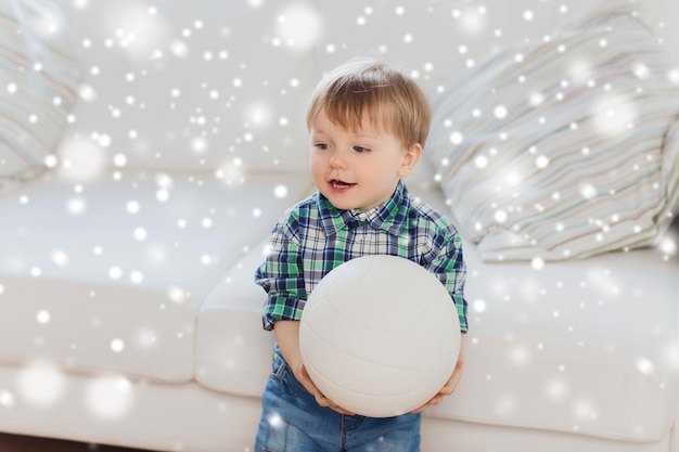 infância e conceito de pessoas - menino feliz com bola em casa sobre a neve