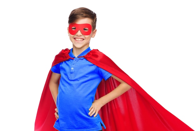 infância, fantasia de carnaval e conceito de pessoas - menino feliz em máscara e capa vermelha de super-herói