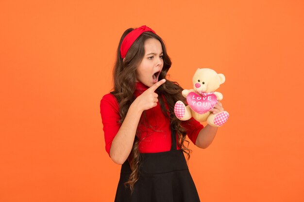 Infância feliz. Amigo imaginário. Menina brincar com o ursinho de pelúcia de brinquedo macio. Cuidado da criança. Memórias de infância. Intelecto emocional. Criança adorável. Linda menina sorridente rosto feliz segurar o brinquedo.