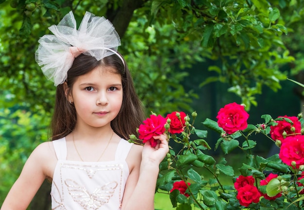 Infancia feliz belleza y moda niño bonito olor rosa flor primavera y verano naturaleza niña en jardín niño disfrutar flor en parque pequeño ángel para novia linda dama