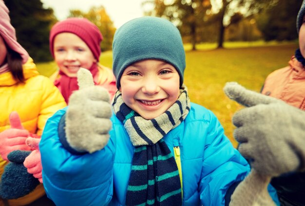 infância, lazer, amizade e conceito de pessoas - grupo de crianças felizes mostrando os polegares no parque outono