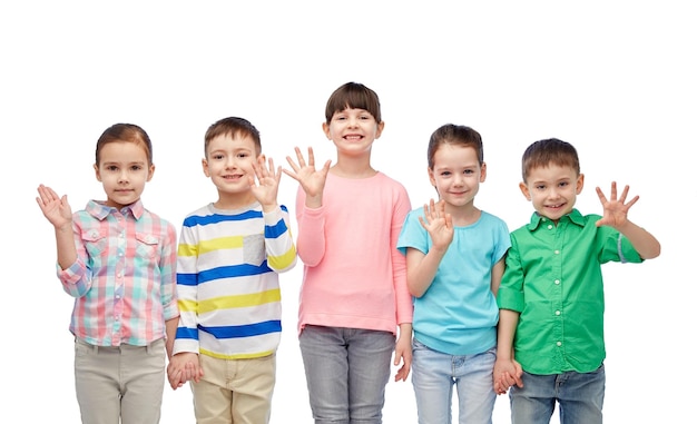 la infancia, la moda, la amistad y el concepto de la gente - grupo de niños pequeños sonrientes felices tomándose de la mano