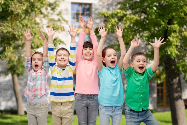 infancia, moda, gesto y concepto de la gente - felices amigos sonrientes levantando puños y celebrando la victoria sobre el fondo del campus de verano
