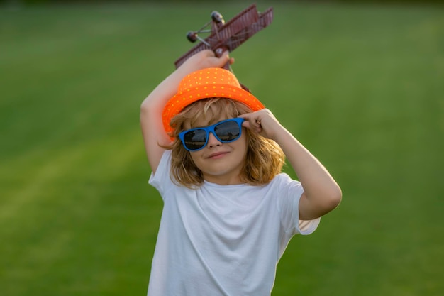 Infância no campo Criança se divertindo com avião de brinquedo no campo Aviador piloto infantil com avião sonha em viajar no verão na natureza