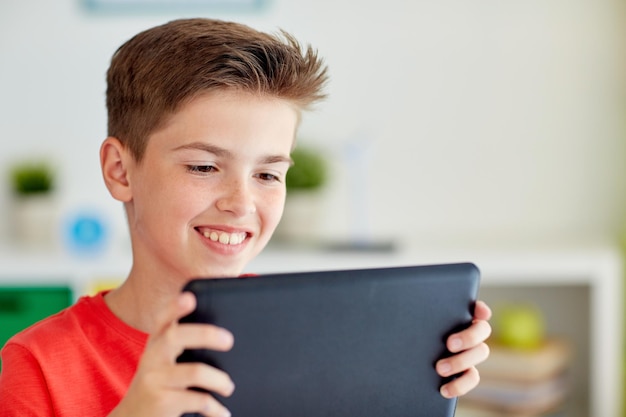 Infância tecnologia e pessoas conceito de close-up de menino sorridente com tablet pc computador em casa