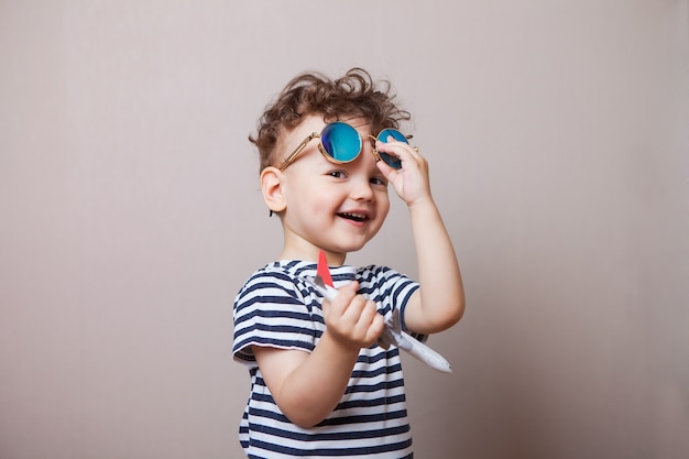 Foto infantil, criança com um avião de brinquedo em suas mãos e óculos de sol. turista