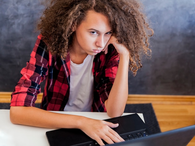 Foto infeliz adolescente usando la computadora portátil en h ome