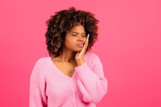 Infeliz e triste jovem afro-americana encaracolada em sofrimento casual de dor de dente sente dor