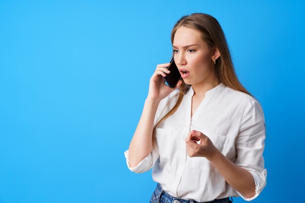 Infeliz mujer hablando por teléfono destacó con malas noticias fondo azul