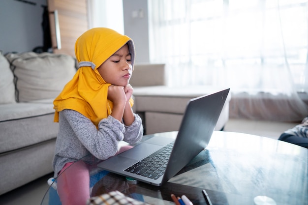 Infeliz niño musulmán mientras estudia desde casa usando la computadora portátil