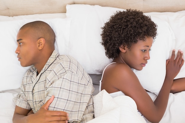 Infeliz pareja acostada en la cama sin hablar