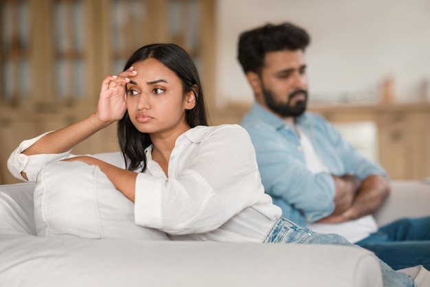 Foto infeliz pareja india teniendo pelea deprimido hombre y mujer sentados en el sofá experimentando