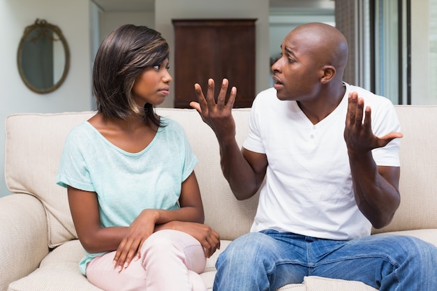 Infeliz pareja teniendo una discusión en el sofá