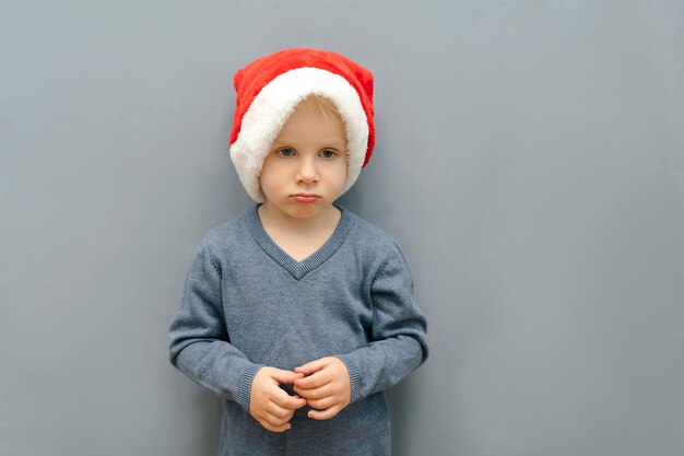 Infeliz sombrío triste niño niño niño en navidad rojo santa claus hat capNew Year Christmas Holidays