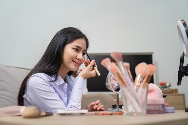 Influencer de belleza asiática aplicando maquillaje en una transmisión de video