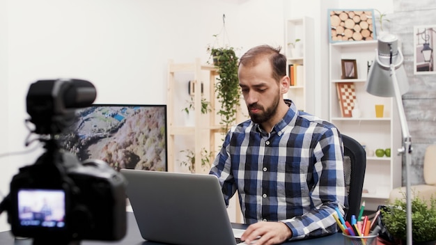 Influencer famoso hablando y revisando una computadora portátil. Creador de contenido creativo. Grabando un nuevo vlog.