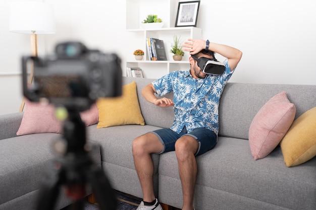 Influencer masculino emocionado usando gafas de realidad virtual por primera vez grabando la experiencia