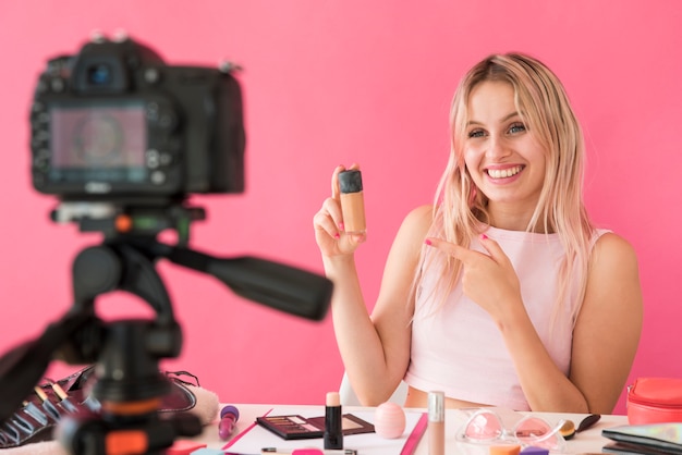 Foto influencer rubia grabando vídeo de maquillaje