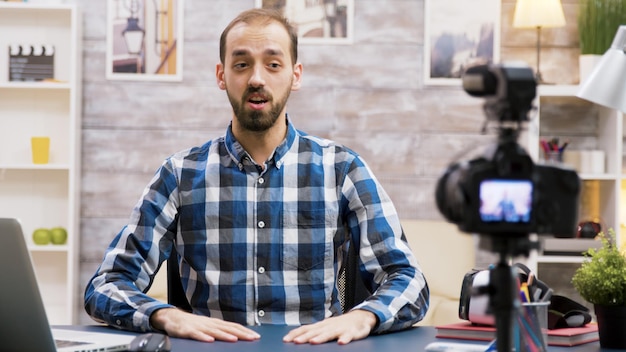 Influenciador animado durante a gravação de seu vlog na sala de estar. Homem criativo famoso.