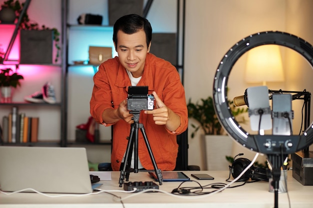 Influenciador asiático configurando la cámara en casa