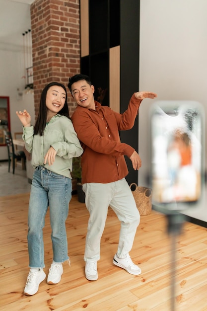 Influenciadores de casais asiáticos gravando vídeo em smartphone dançando em vloggers de estilo de vida da câmera criando conteúdo para blog