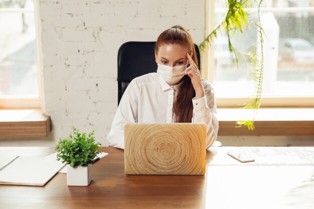 Informationen erhalten Frau, die während Coronavirus oder COVID19 allein im Büro arbeitet