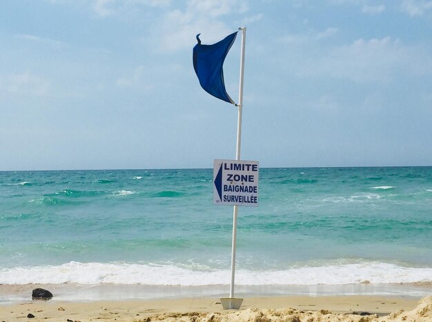 Informationsschild am Strand gegen den Himmel