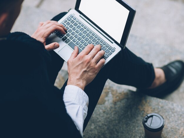 Informationstechnologie. Online-Bildung. Männlicher Student, der an Laptop mit weißem Bildschirm arbeitet.