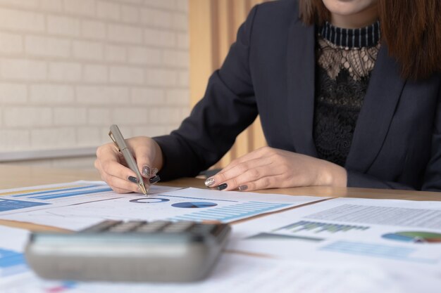 Informe financiero del balance financiero de la mujer trabajando con documentos gráficos.