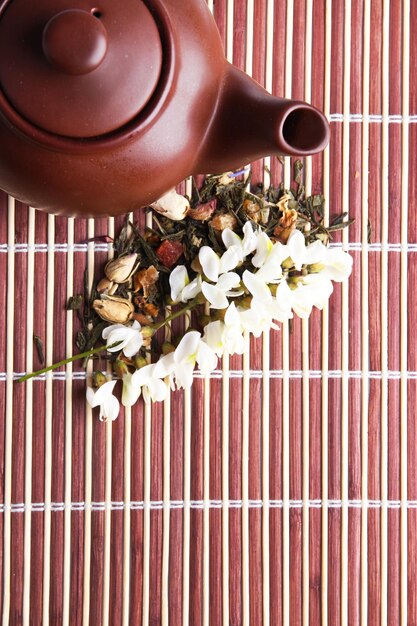 Foto infusão de chá floral natural de ervas com ingredientes de flores secas em fundo de tapete de bambu