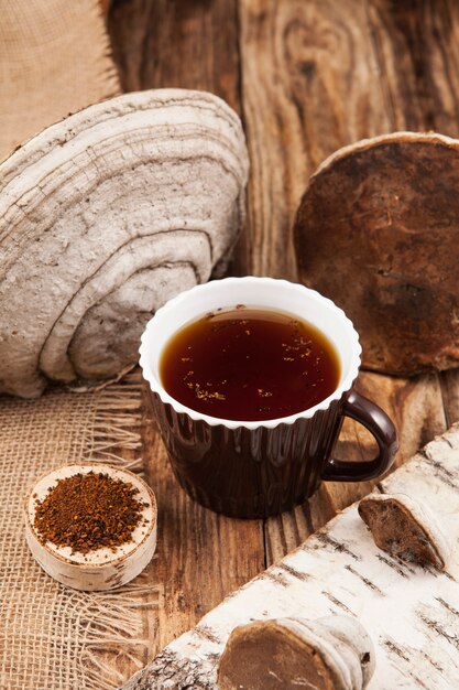 Infusão de cogumelos Chaga em copo sobre mesa de madeira rústica