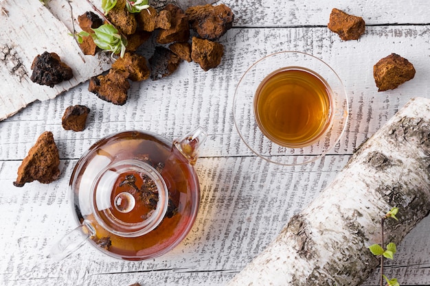 Infusión de setas Chaga en tetera de vidrio en tablero blanco.